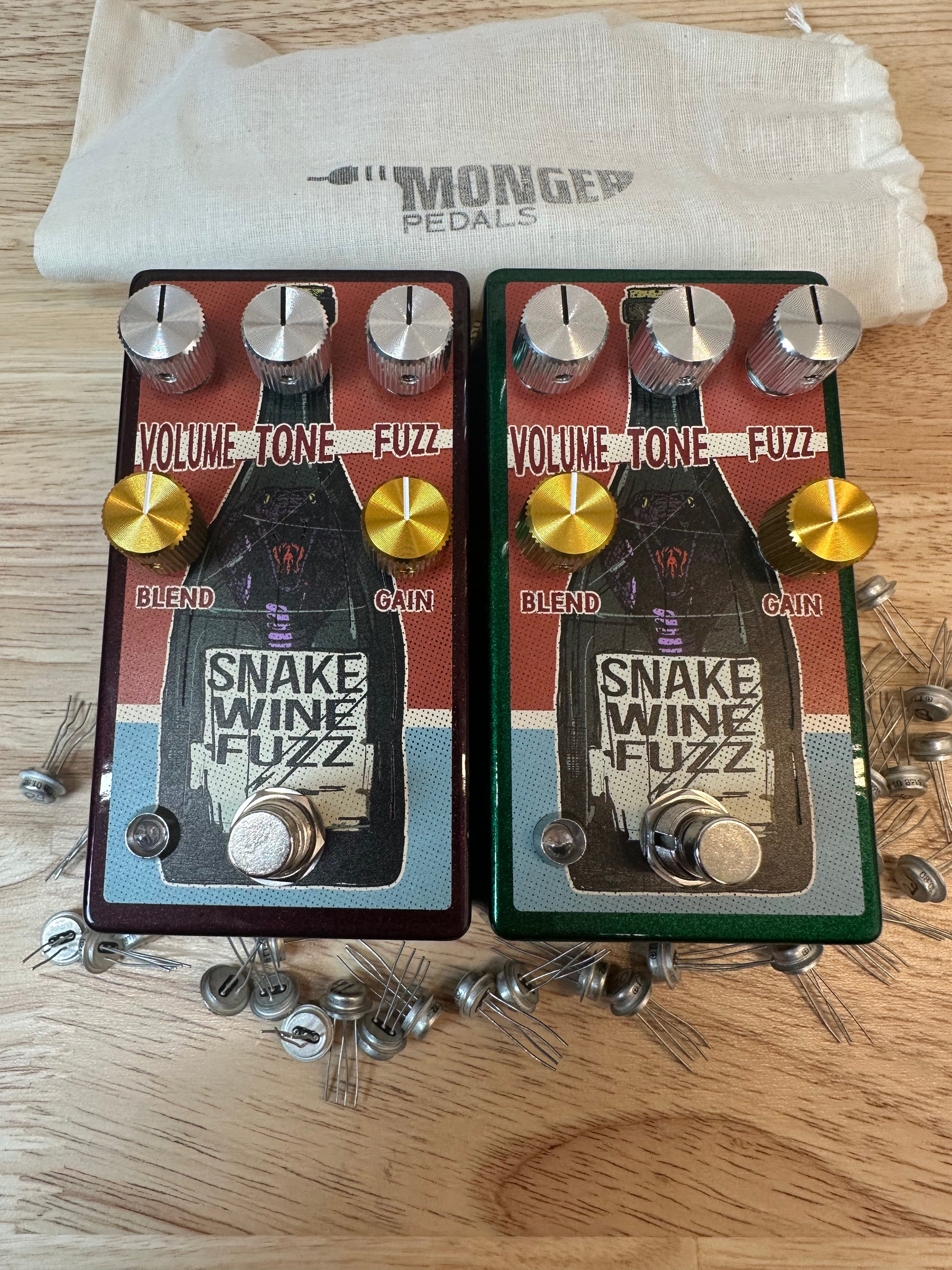 Both versions of The Germanium Snake Wine Fuzz side by side with their dust bag above 